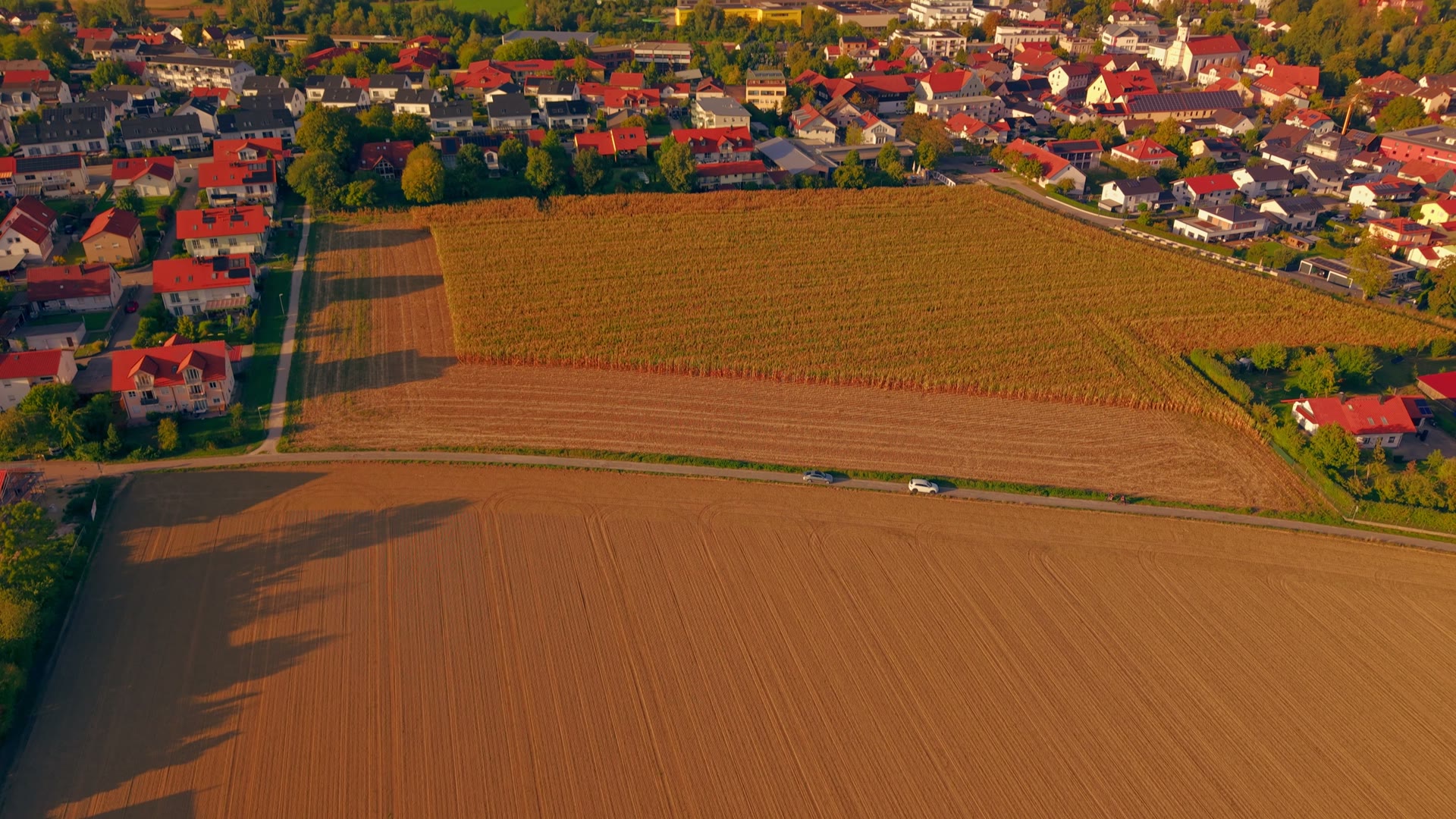 Drohnenaufnahme: Luftbild einer bayerischen Gemeinde mit Feldern und Wohnhäusern im Abendlicht